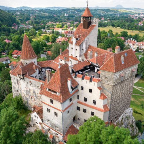 Aerial drone view of The Bran Castle in Romania. Medieval castle with tourists inside it in Carpathians, green trees around