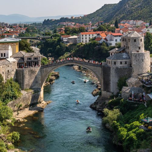 This photo captures a river running through Mostar city, with a prominent Old Bridge in the background, Bosnia and Herzegovina
